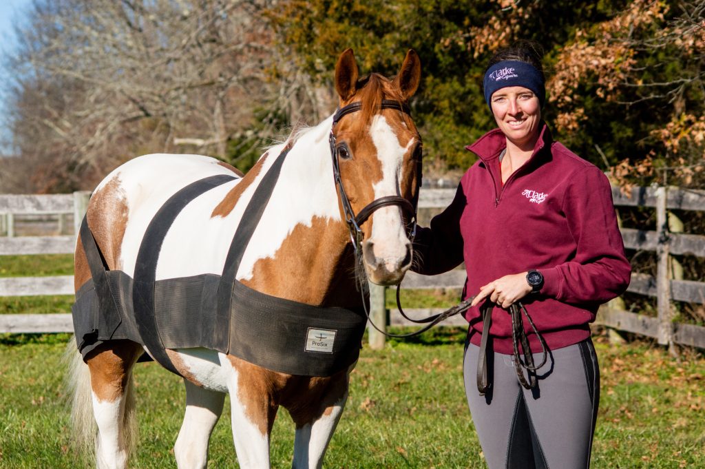 Kendra Clarke standing next to her horse wearing the pro six equine.